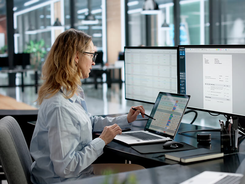 woman using two monitors and a laptop