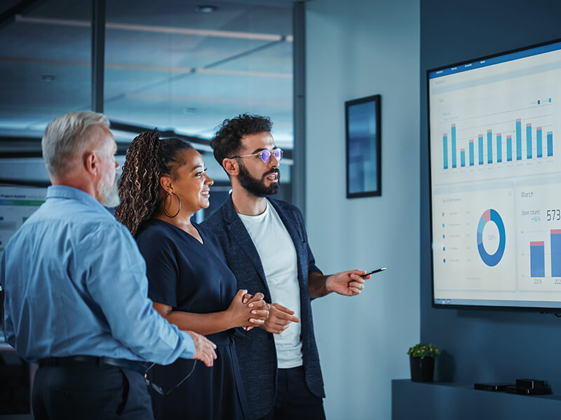 group of three people viewing data on a projector