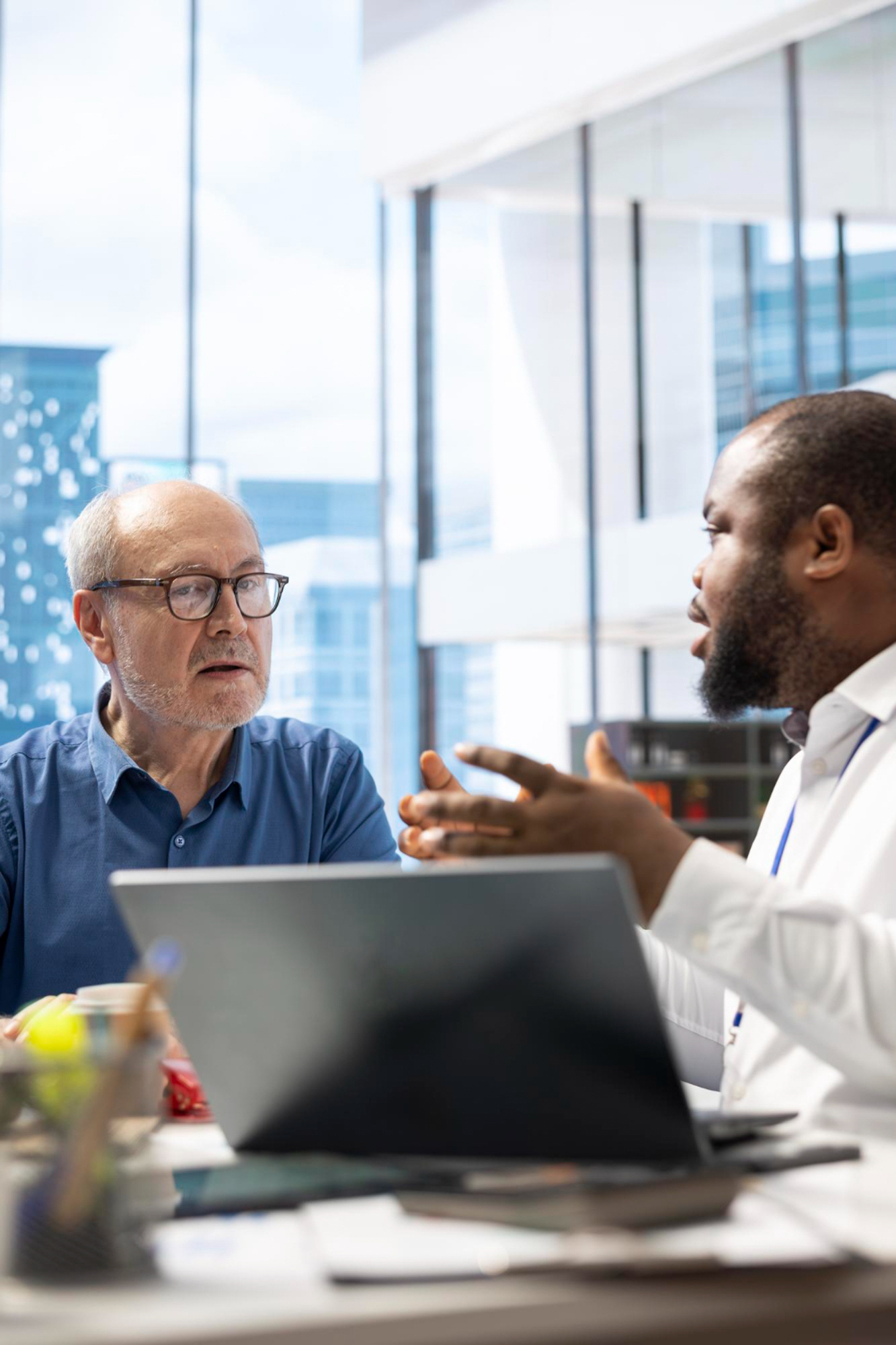 Two men communicating ideas while using a laptop