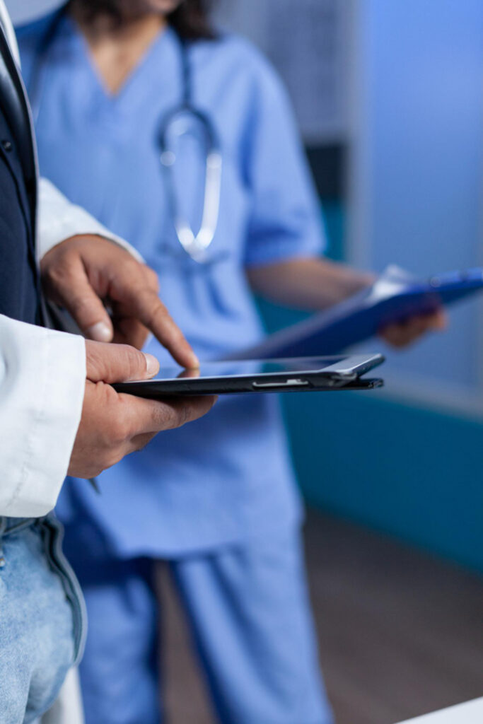 A doctor pointing at a tablet along with a nurse holding a clipboard
