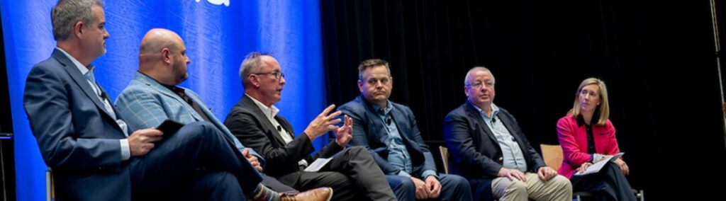 A group of six people speaking at a panel at HFMA
