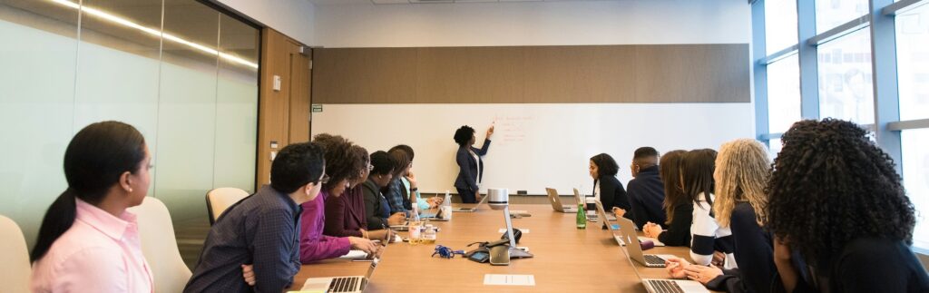 A group of people in a meeting with a woman giving a presentation