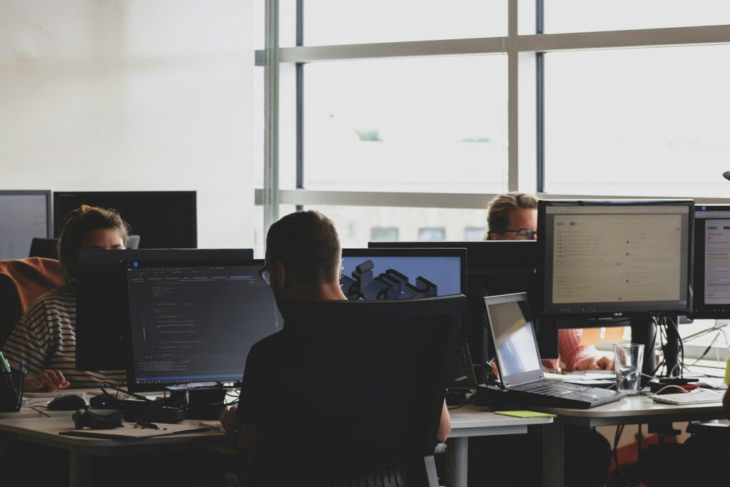 Three people using computer monitors