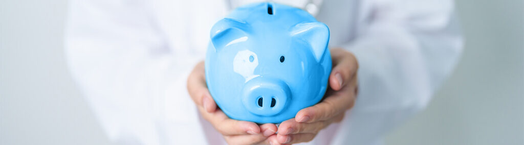 A blue piggy bank that is being held with two hands by a person in a white coat