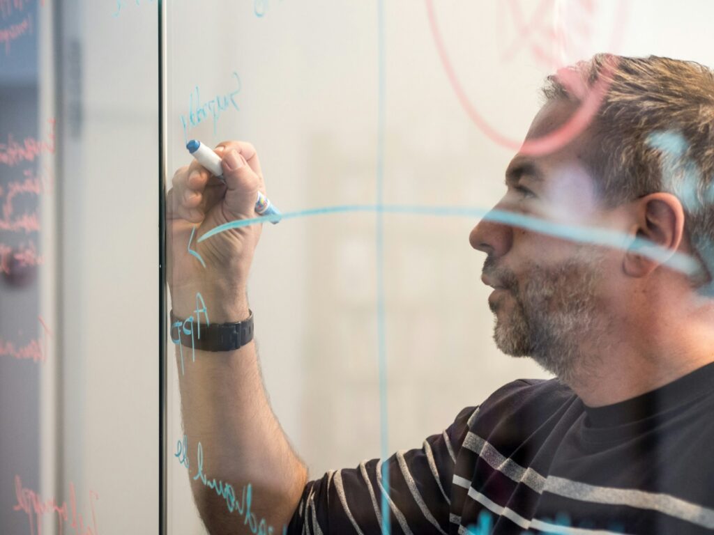 A person writing on a glass board.