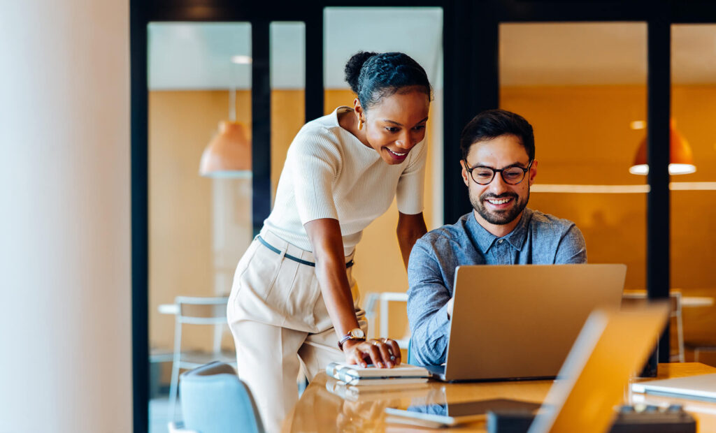 woman and man smiling and using a computer