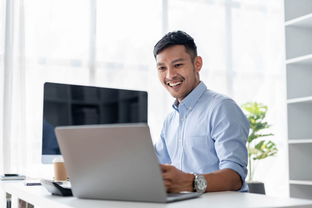 man at desk smiling at laptop