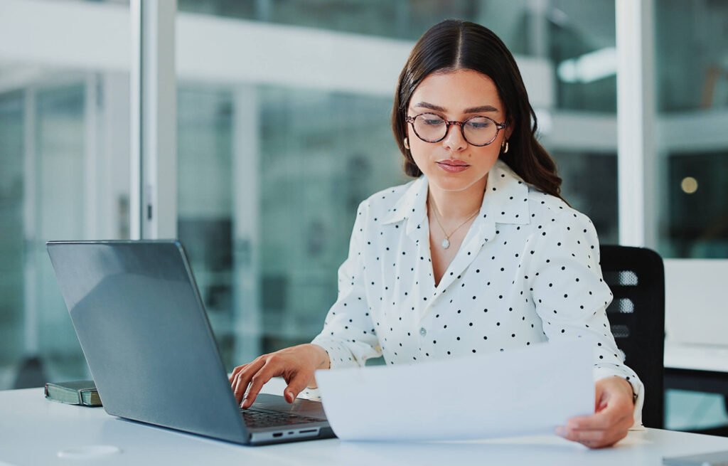 woman using a laptop and a document