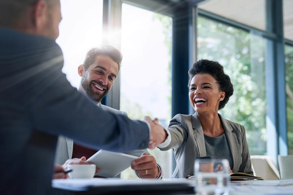 woman and man smiling while shaking hands