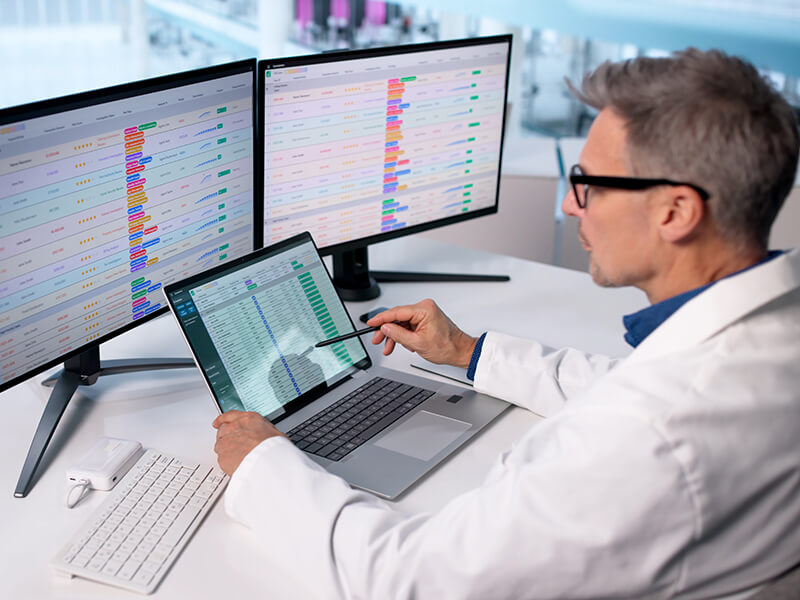 doctor sitting inf ront of screens looking at clinical data