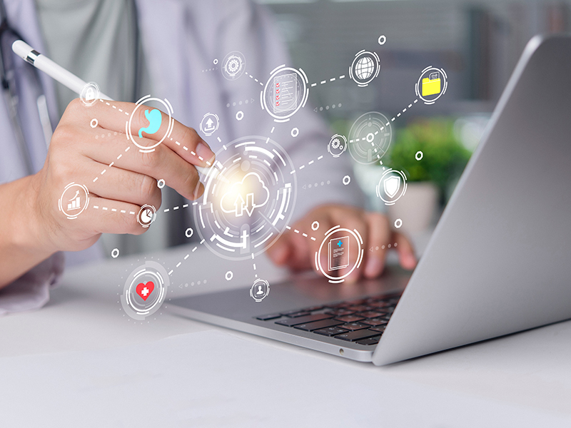 doctor typing on laptop with icons floating over the keyboard